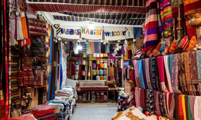 Colourful textiles and fabrics displayed in a vibrant market setting.